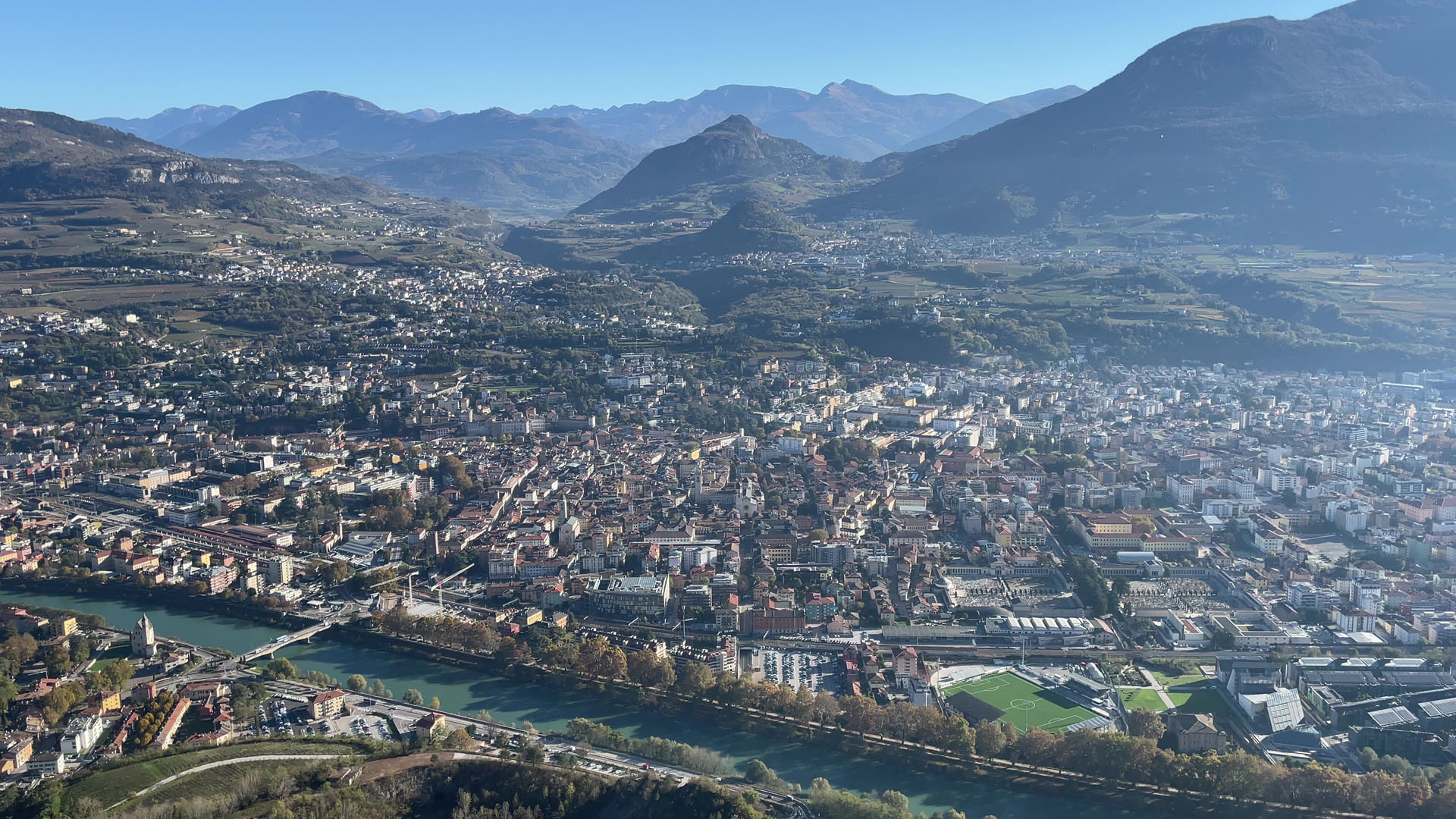 Una veduta aerea della città di Trento: in primo piano il fiume Adige e sullo sfondo le montagne