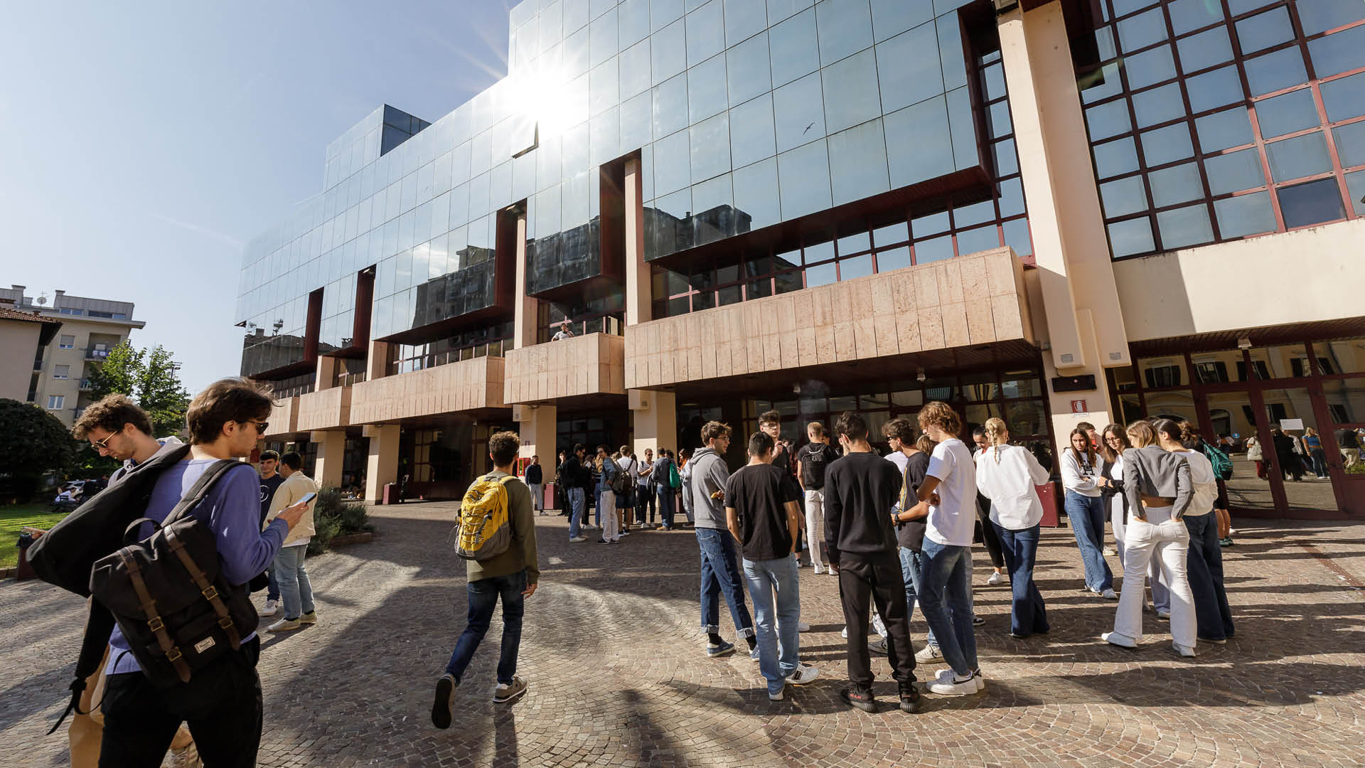 Il cortile del Dipartimento di Economia e Management: sullo sfondo l'edificio, con pareti a specchio, in primo piano gruppi di studenti parlano tra di loro