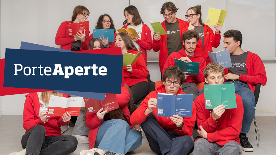 Gli studenti e le studentesse orientatori: seduti su dei gradoni, leggono le guide ai corsi e indossano le felpe rosse di Orienta 