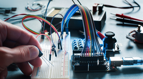 Prototipazione elettronica su breadboard con microcontrollore, cavi jumper e sensori nel laboratorio di elettronica